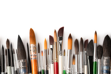 Mix of paint brushes in a row isolated on a white background.  Top view.