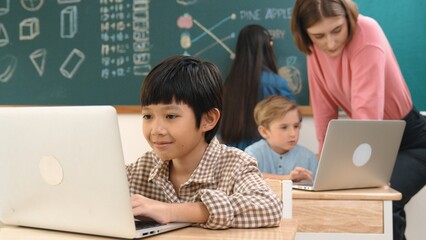 Cute boy coding engineering prompt while attractive girl drawing picture at blackboard. Caucasian...
