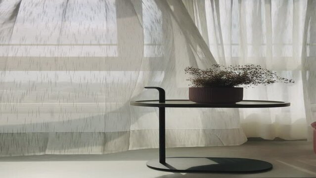Bright morning sunlight from the open window through the curtains with a modern table and vase. white curtains on the windows gently blowing in the wind in beautiful wave