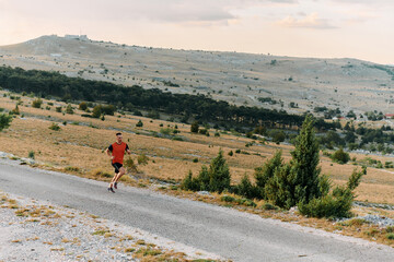 Determined Athlete Running Through Rugged Mountain Terrain at Sunrise.