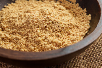 Peanut flour in a wooden bowl. The fine golden nut powder is a versatile ingredient for baking