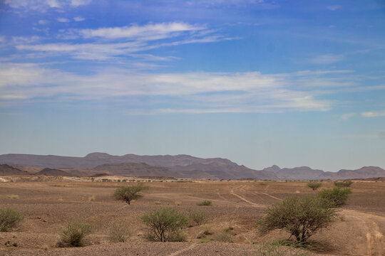 Dry open countryside and low hills beneath a broad sky