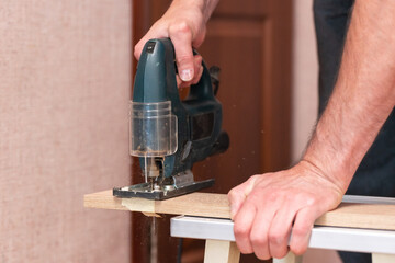 A worker cuts a board with a jigsaw