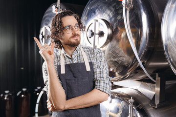 Portrait smile bearded man brewer in apron on background beer tank. Concept owner small business of craft brewery