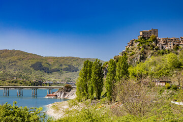 Fototapeta premium A view of Lake Turano, from the village of Castel di Tora, Rieti, Lazio, Italy. The bridge crossing the lake, surrounded by green mountains. Blue sky in summer.