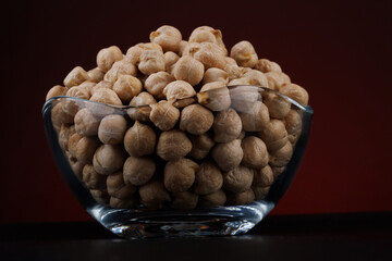 Glass cup with chickpeas on a beautiful illuminated red background.