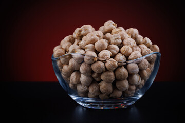 Glass cup with chickpeas on a beautiful illuminated red background.