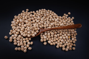 Wooden spoon with chickpeas and chickpeas scattered around.