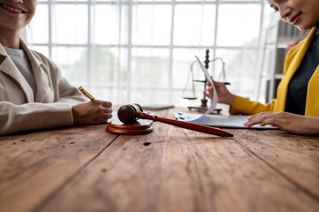 Two women are sitting at a table with a gavel and a piece of paper