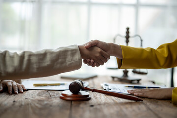 Two people shaking hands in front of a judge's gavel