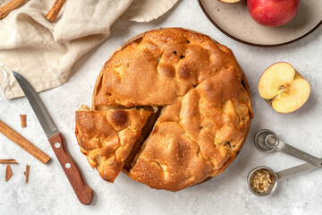 Traditional apple pie on a wooden plate on a dark culinary background. Charlotte pie on a platter in close-up. Delicious homemade cakes on the kitchen table top view