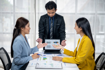 Three people are sitting at a table with a laptop in front of them
