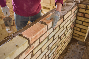 Construction worker is expertly laying bricks at the construction site with precision and skill