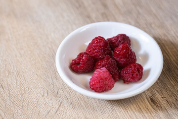 raspberries in bowl on wooden floor