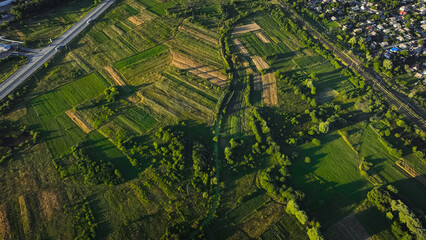 Fototapeta premium aerial country side landscape harvest fields park and trees green environment outskirts space in end of summer season August month time evening contrast lighting with shadow from sun