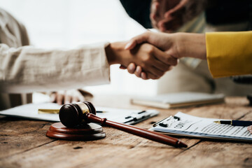Close up of hands Lawyers explain and discuss matters of law then shakehands after and dealing contract agreement to clients discuss for prepare for the trial. gavel hammer and scales of justice.