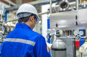 Asian engineer working at Operating hall,Thailand people wear helmet  work,He worked with diligence and patience,she checked the valve regulator at the hydrogen tank.
