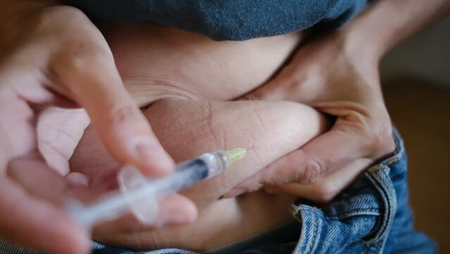 A woman injecting hormones into her stomach at home, illustrating hormone therapy and in vitro fertilization (IVF) treatment