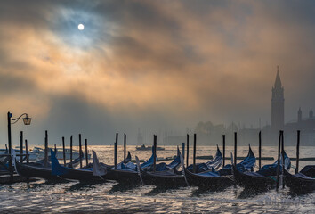 Naklejka premium Gondolas in Venice at sunrise in morning fog. Veneto, Italy..