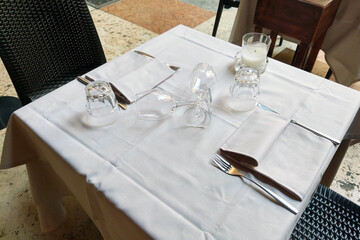 Elegant Table Setting with Upside-Down Glassware and Candle Decor in an Outdoor Restaurant