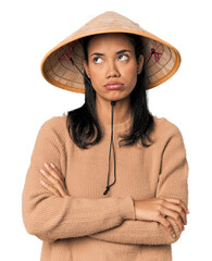Young Filipina with Vietnamese hat tired of a repetitive task.