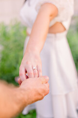 A couple is holding hands, and she stands apart from him.