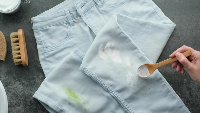 Homemade eco-friendly removing of stains on clothes with baking soda. Woman's hand applies baking soda powder for eco-friendly stain removal. Zero waste concept. 4k video