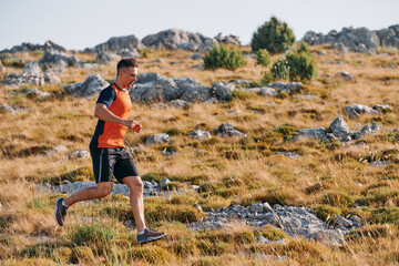 Obraz premium Determined Athlete Running Through Rugged Mountain Terrain at Sunrise.