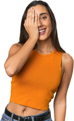 Hispanic young woman having fun covering half of face with palm.