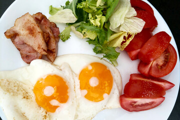 Healthy Breakfast Plate with Bacon, Sunny-Side-Up Eggs, Fresh Lettuce, and Sliced Tomatoes Ideal for Nutrition, Food Blogs, and Recipe Design