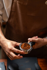Barista holds a portafilter making coffee with a coffee machine. The process of making cuppuccino. hand with tamper