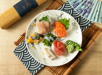 Assorted Comprehensive Sashimi with Dory sashimi, salmon sashimi, Tuna fish, swordfish served in plate isolated on napkin top view on wooden background of Japanese food