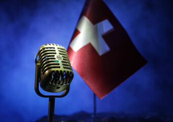 Microphone on a background of a blurry flag of Switzerland close-up. dark table decoration