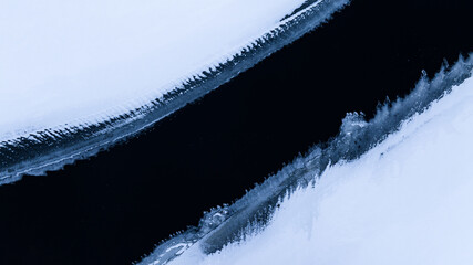 Drone view of flowing river with snow covered sides © arai