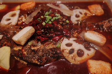 A close-up shot of a flavorful Sichuan hot pot brimming with a variety of ingredients. The dish...