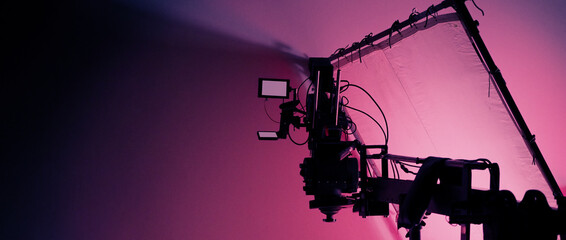 Professional video shoot studio. Behind the scenes of video commercial production shooting set. Silhouette of camera and equipment in studio. Making of online film advertising on set. Selective focus. © gnepphoto