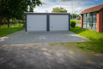Obraz premium a newly built double garage with roller doors stands under a tree