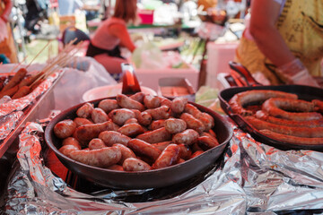 A close-up view of sizzling grilled sausages being prepared at an outdoor food market.