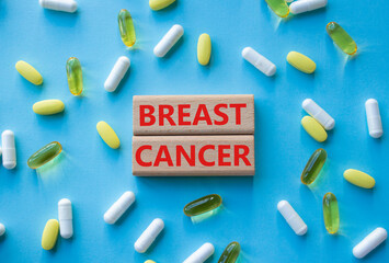 Breast cancer symbol. Wooden blocks with words Breast cancer. Beautiful blue background with pills....