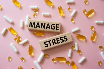 Manage stress symbol. Concept word Manage stress on wooden blocks. Beautiful pink background with pills. Medicine and Manage stress concept. Copy space