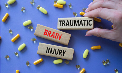 Traumatic Brain Injury symbol. Concept words Traumatic Brain Injury on wooden blocks. Beautiful purple background with pills. Doctor hand. Healthcare and Traumatic Brain Injury concept. Copy space.