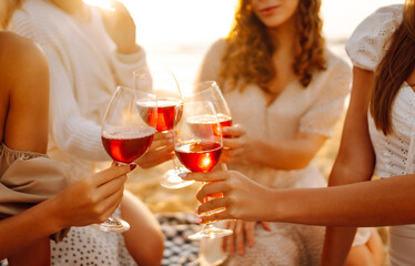 Hen party on the beach. Young ladies with glasses of wine embracing posing standing on the beach. Vacation, relax.