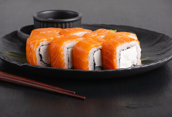 Philadelphia roll with salmon and cheese on plate on dark table