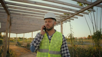 Experienced Caucasian man male guy uniform businessman specialist environmental engineer calling talking mobile phone smartphone call discuss business construction plan outside rural farmland village