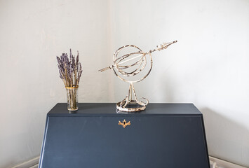A weather vane on a table next to purple flowers