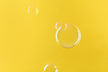 Beautiful transparent soap bubbles on yellow background