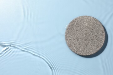 Presentation of product. Stone podium in water on light blue background, top view. Space for text