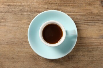 Tasty coffee in cup on wooden table, top view