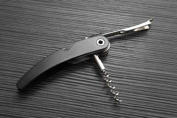 One corkscrew (sommelier knife) on black wooden table, top view