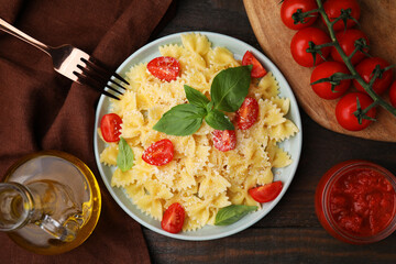 Tasty pasta with tomato, cheese and basil served on wooden table, flat lay